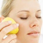 Close-up of a woman rubbing half a lemon to her cheek