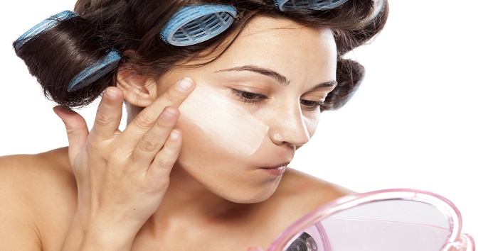 beautiful woman with curlers applied poorly chosen foundation